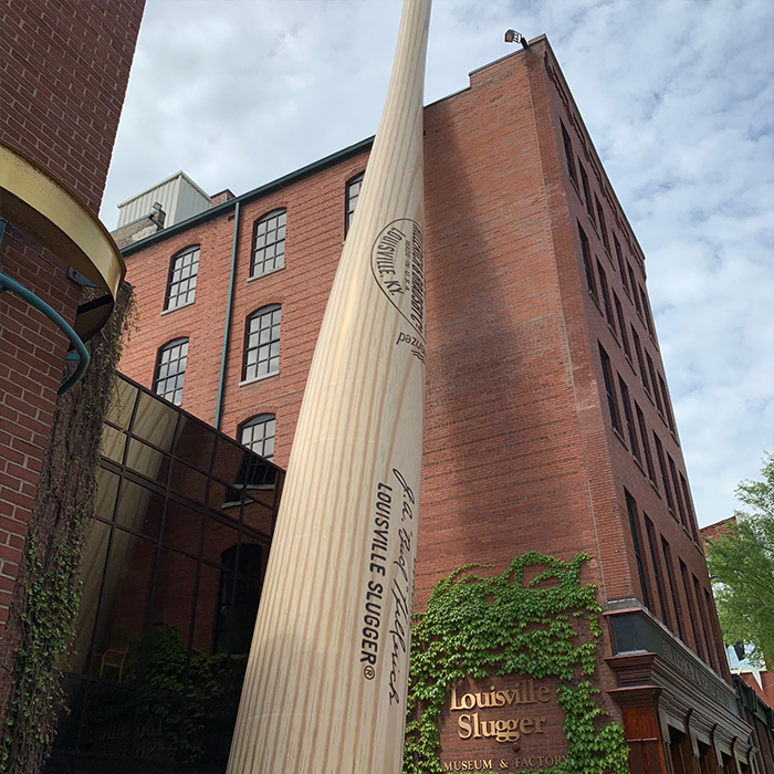 Statue of a baseball bat in front of a brick building
